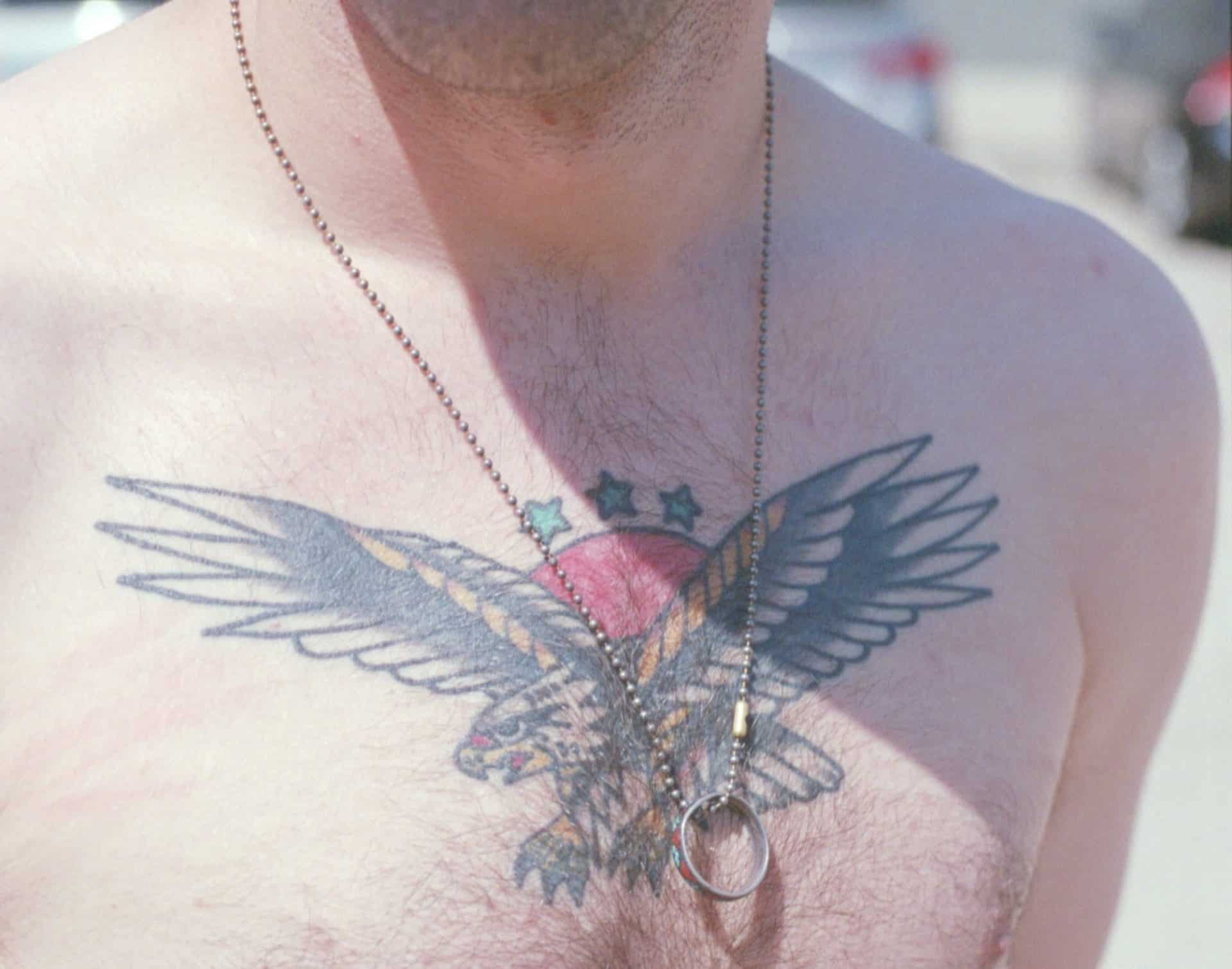 Un hombre con un águila tatuada en el pecho.